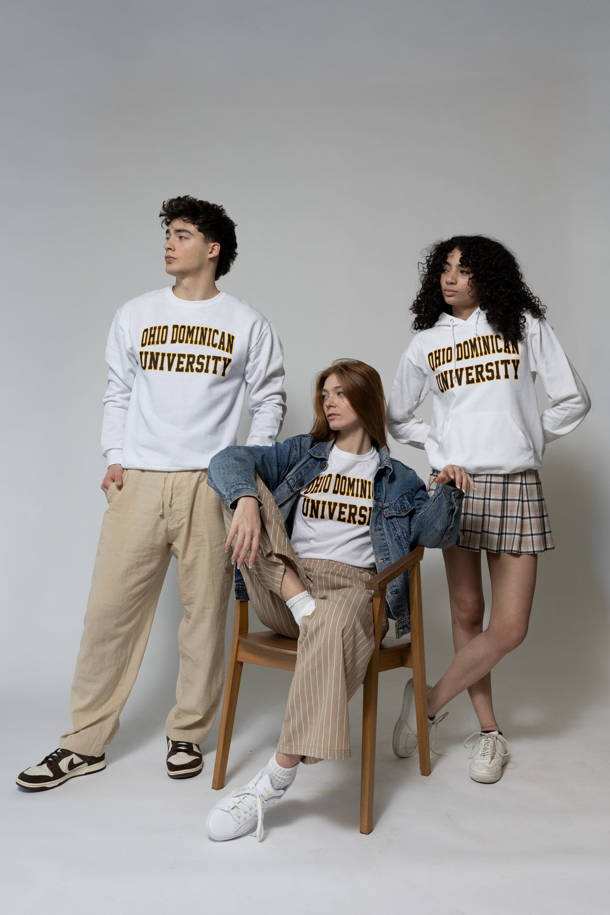Three people wearing 'Ohio Dominican University' clothing on a plain background